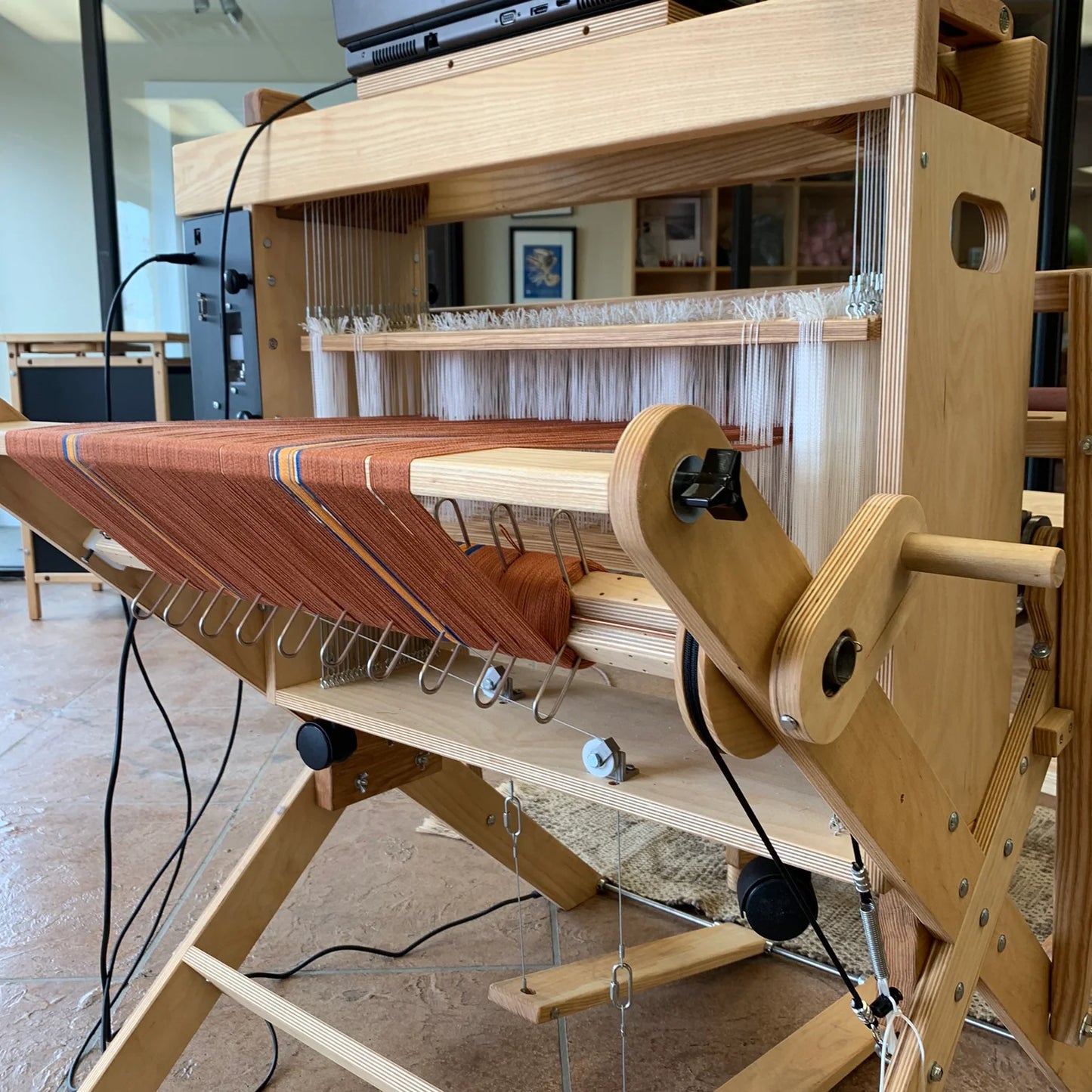 Detailansicht der AVL Workshop Dobby Loom mit aufgezogenem Kettgarn, Kettbaum und Compu-Dobby® 5 Steuerung während des Webprozesses