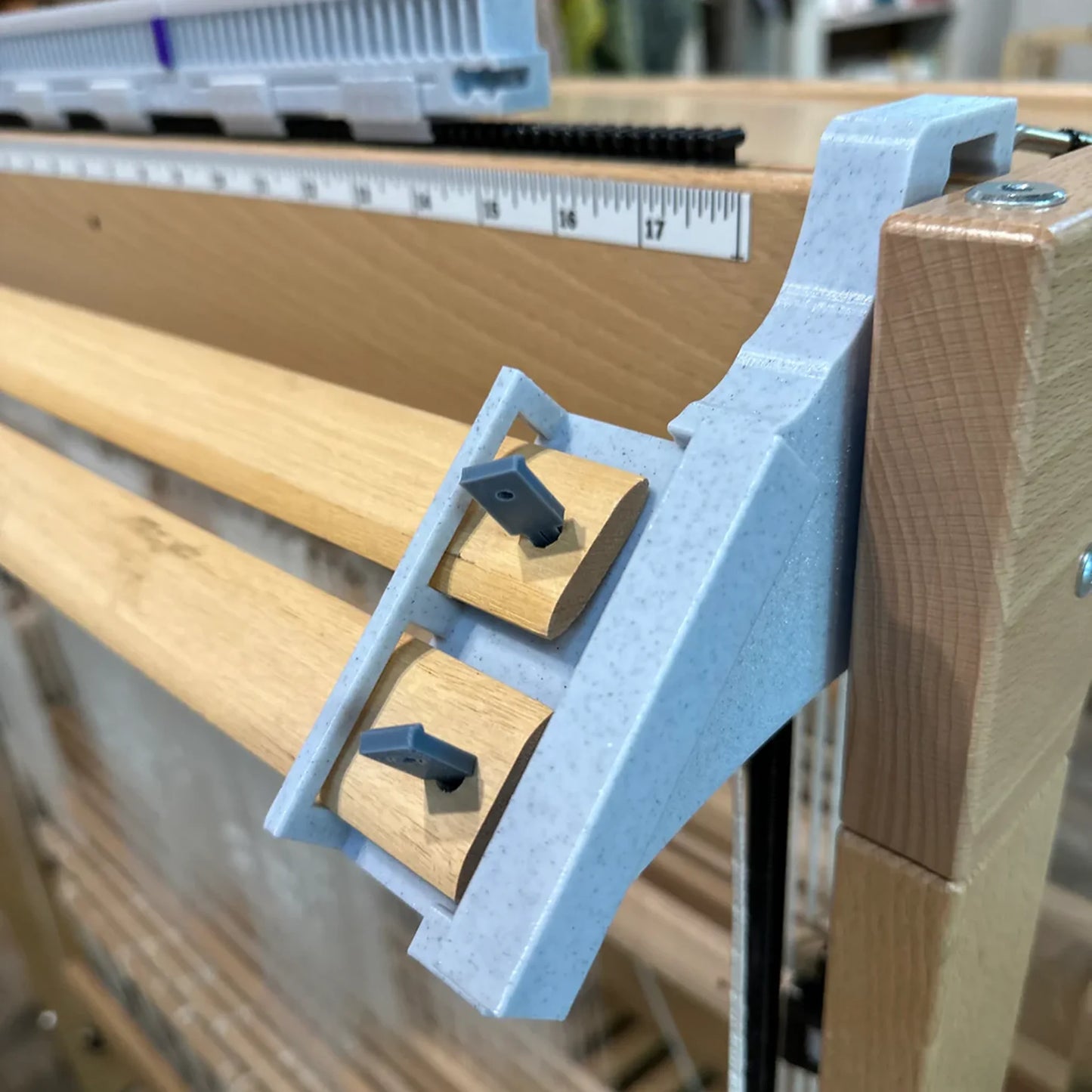 LoftyFiber Helping Hands am Louet Spring Webstuhl – Nahaufnahme der grauen Kunststoffhalterung mit Arretierungsstiften an den Webstäben