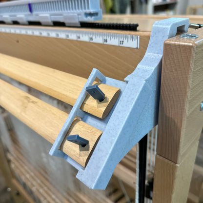LoftyFiber Helping Hands am Louet Spring Webstuhl – Nahaufnahme der grauen Kunststoffhalterung mit Arretierungsstiften an den Webstäben