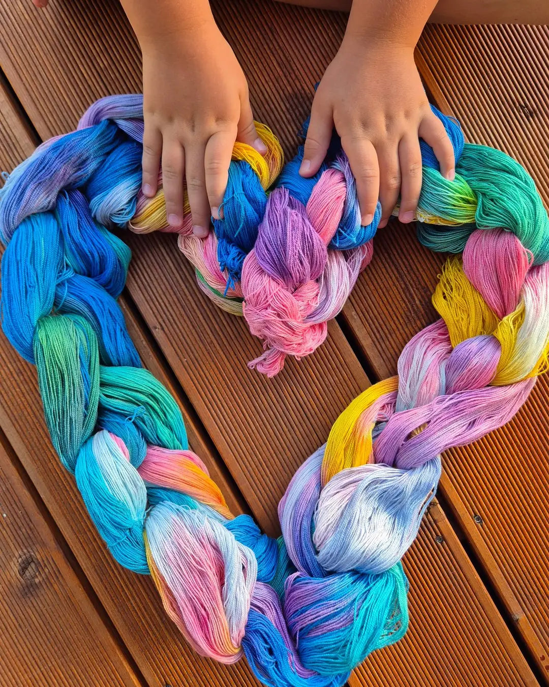 Colourful hand-dyed yarn skeins braided into a heart, result of a yarn dyeing course in Poland